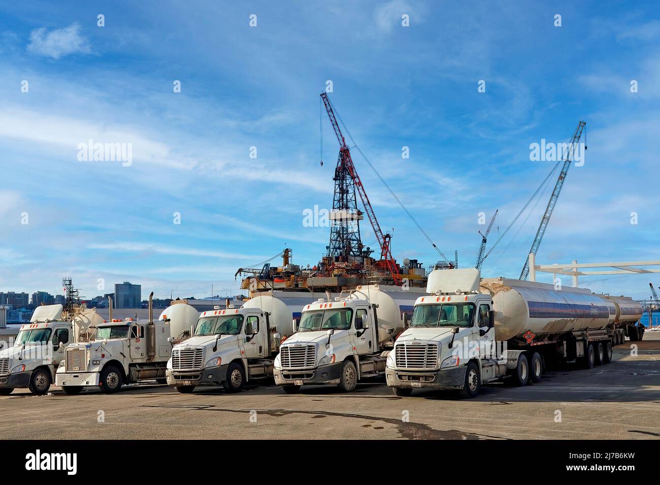 Dartmouth, NS, Kanada - Row of Irving Oil Trucks mit Ölplattform im Hafen von Halifax. Halifax ist im Hintergrund zu sehen. Stockfoto