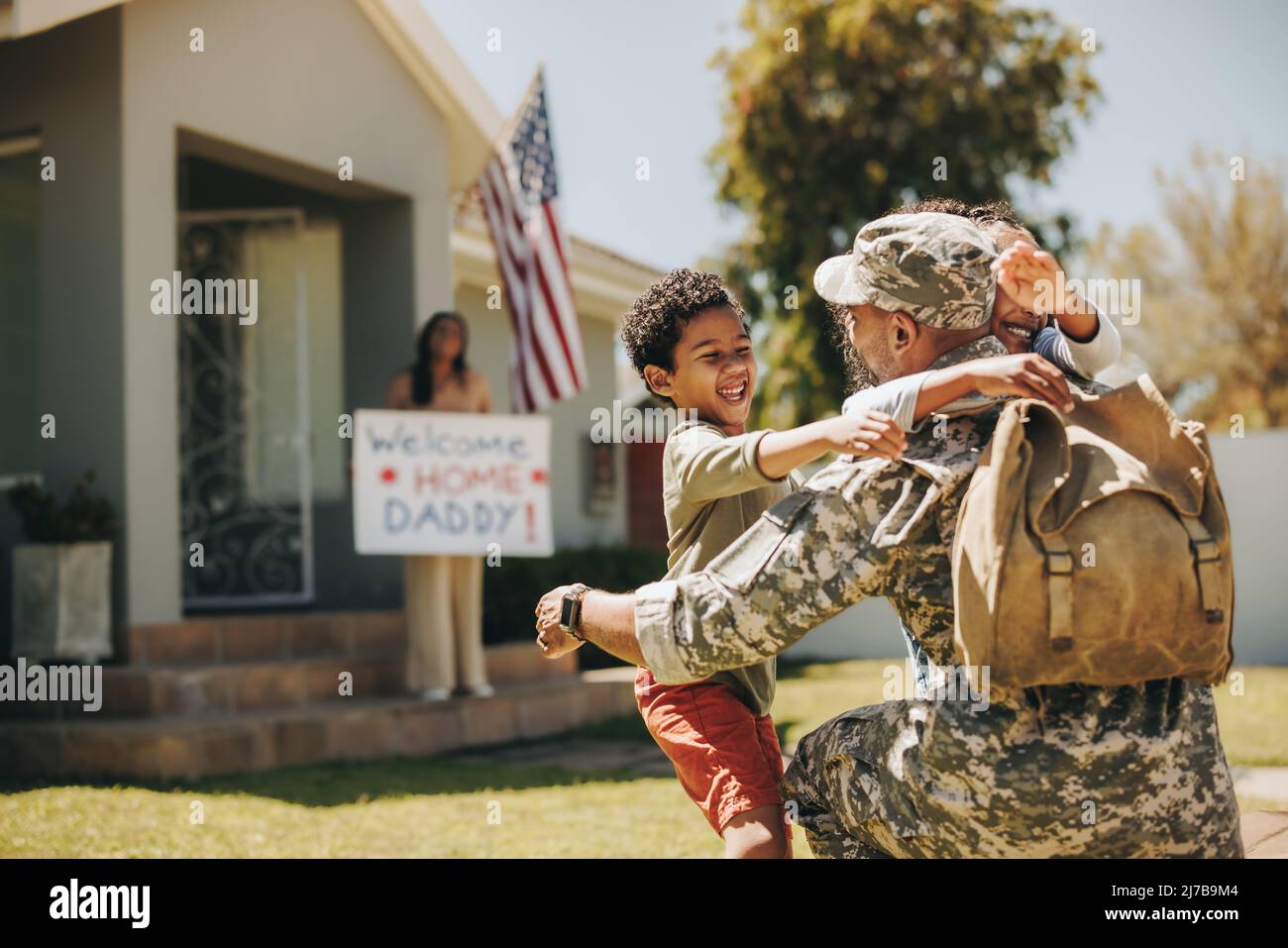 Militärvater, der sich zu Hause mit seiner Familie wiedervereinigt. Amerikanischer Soldat umarmte seine Kinder, nachdem er von der Armee nach Hause zurückgekehrt war. Militärangehöriger erhält ein w Stockfoto