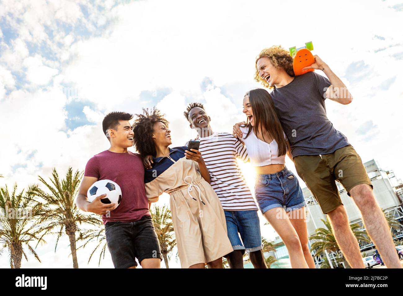 Vereinigte Gruppe von multiethnischen jungen erwachsenen Freunden, die gemeinsam im Freien lachen Stockfoto