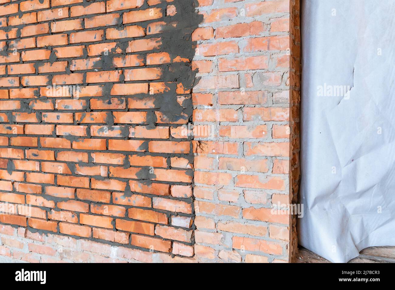 Der geheime Raum in der Wand ist zugemauert. Bunker in einem privaten Haus. Frisch verlegte rote Keramikmauer Stockfoto