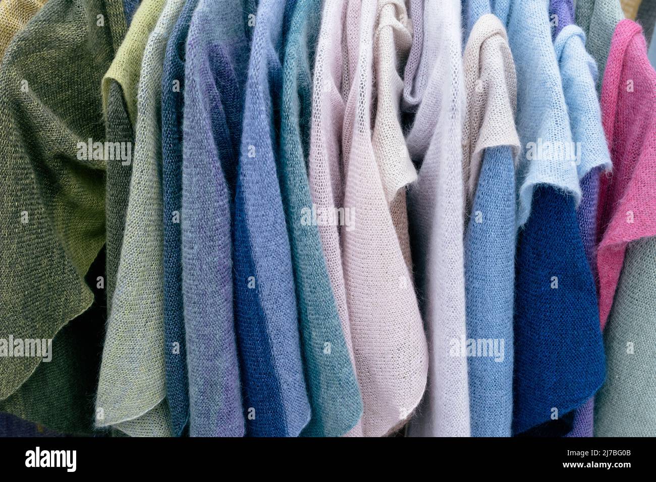 Im Laden hängen mehrfarbige Strickpullover und Häkelpullover für Damen, Jacken an Kleiderbügeln. Stockfoto