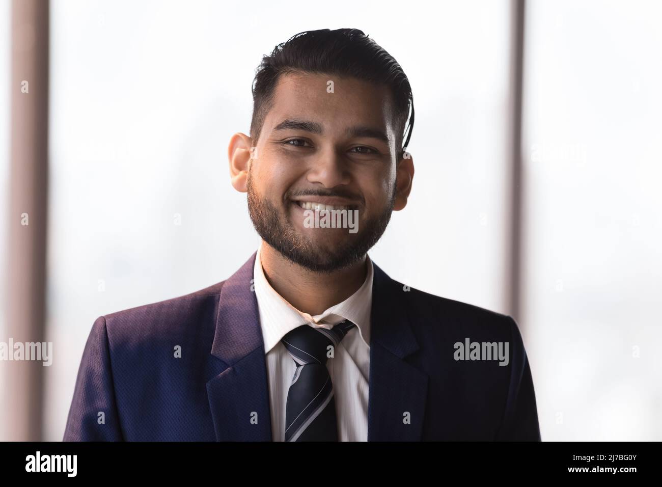 Glücklicher junger indischer Geschäftsmann in formellem Anzug Kopf geschossen Porträt Stockfoto