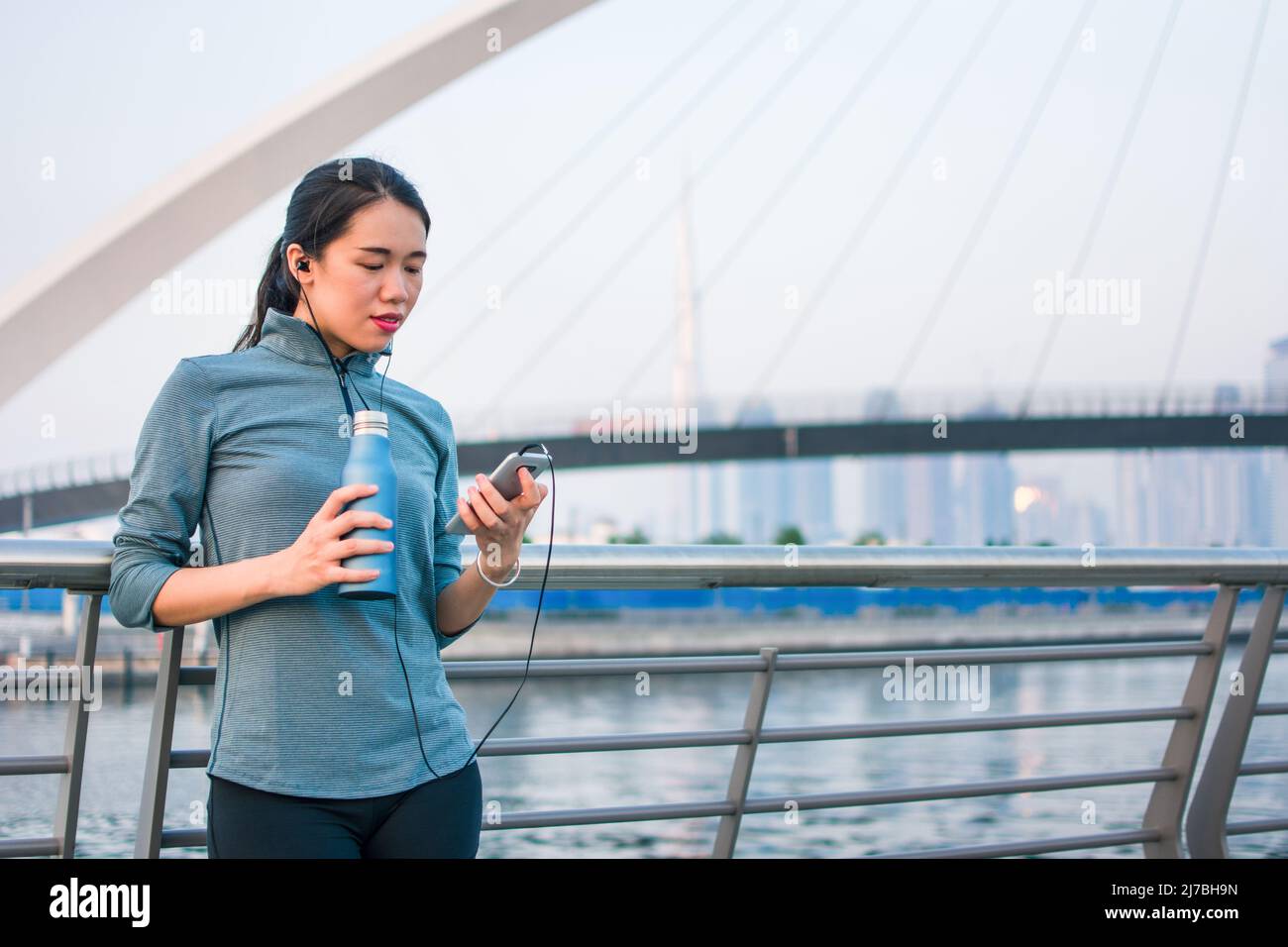 Fit asiatische Frau, die sich von einem Outdoor-Workout ausruhen und draußen in Dubai laufen Stockfoto