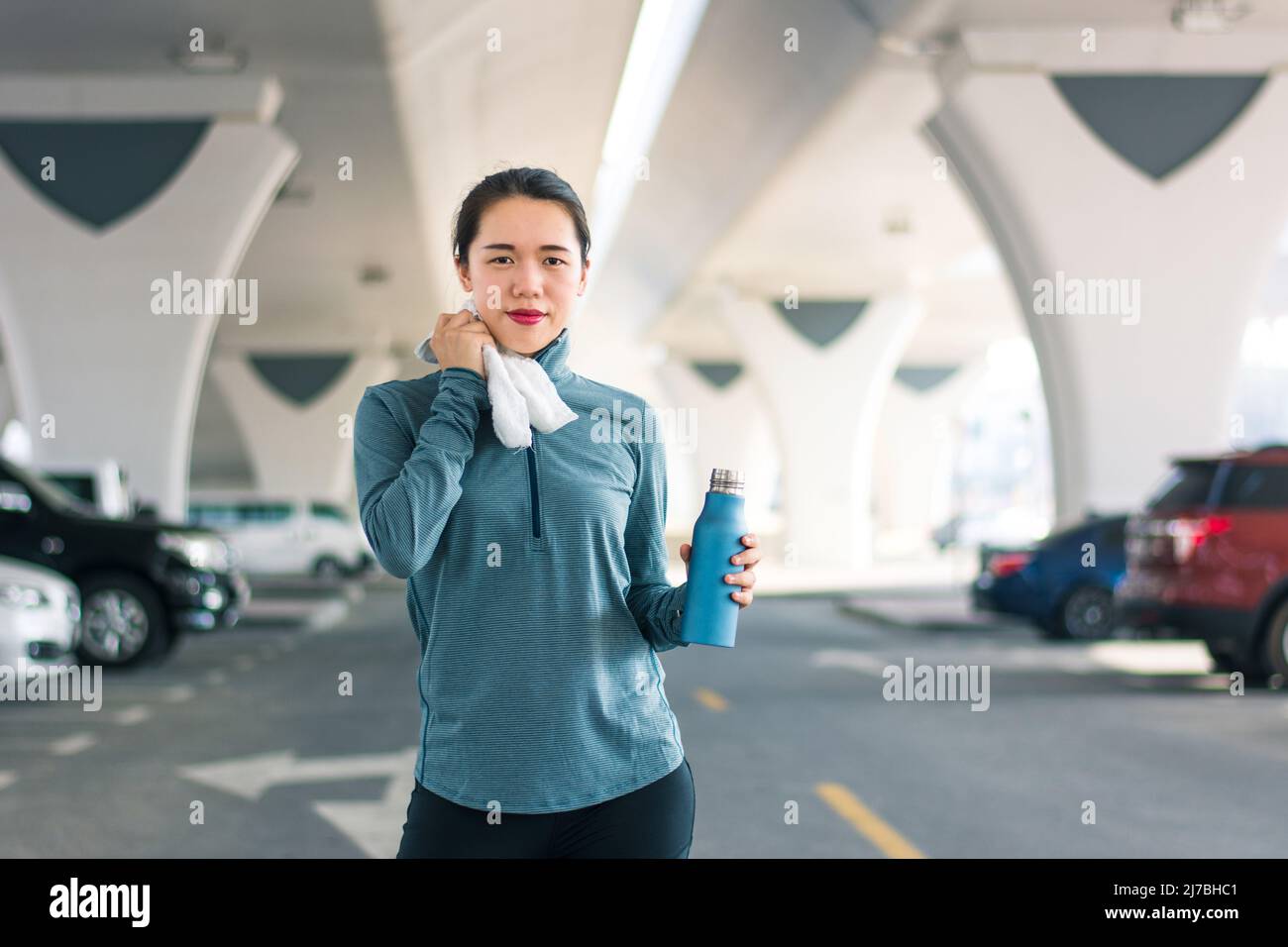 Asiatische Frau, die beim Joggen in der Stadt auf dem Parkplatz im Stadtgebiet ausruhte. Laufen und gesunde Outdoor-Zeit. Fit weibliche Person, die sportliche Aktivität Stockfoto