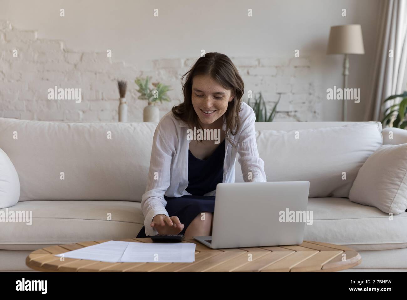 Positiv zufriedene junge Mieterin, die buchhalterische Arbeit macht Stockfoto