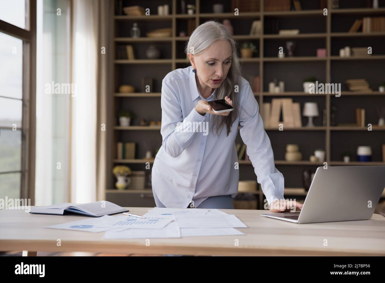Serious beschäftigt reifen Business professionelle Frau am Tisch stehen Stockfoto