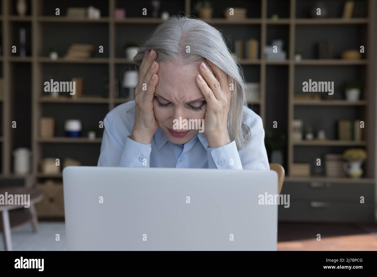 Müde frustrierte ältere Geschäftsfrau, die unter Kopfschmerzen leidet Stockfoto