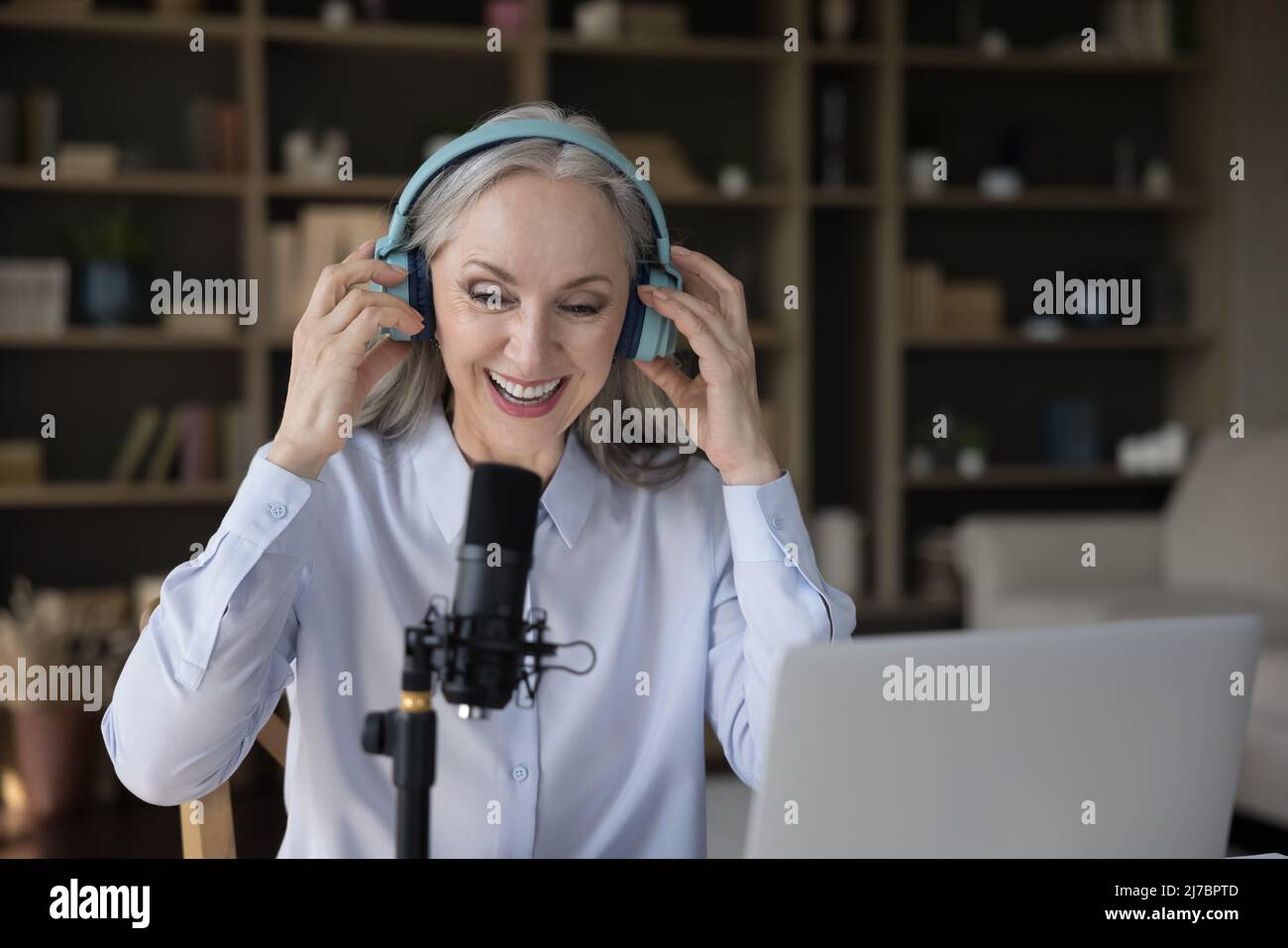 Reife Bloggerin Frau in Kopfhörer sprechen am professionellen Mikrofon Stockfoto