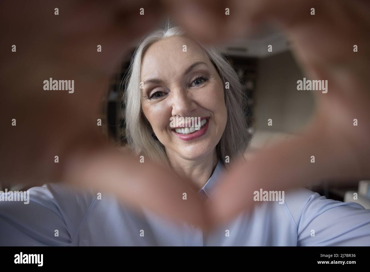 Glückliche, dankbare, grauhaarige Dame, die die Kamera anschaut Stockfoto