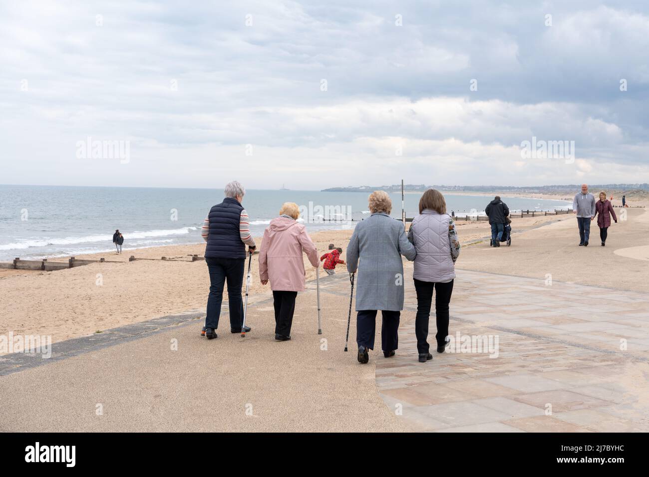 Eine Gruppe britischer Senioren, die mit Hilfe auf der Promenade spazieren gehen und Bewegung und einen gesunden Lebensstil im späteren Leben veranschaulichen. Stockfoto