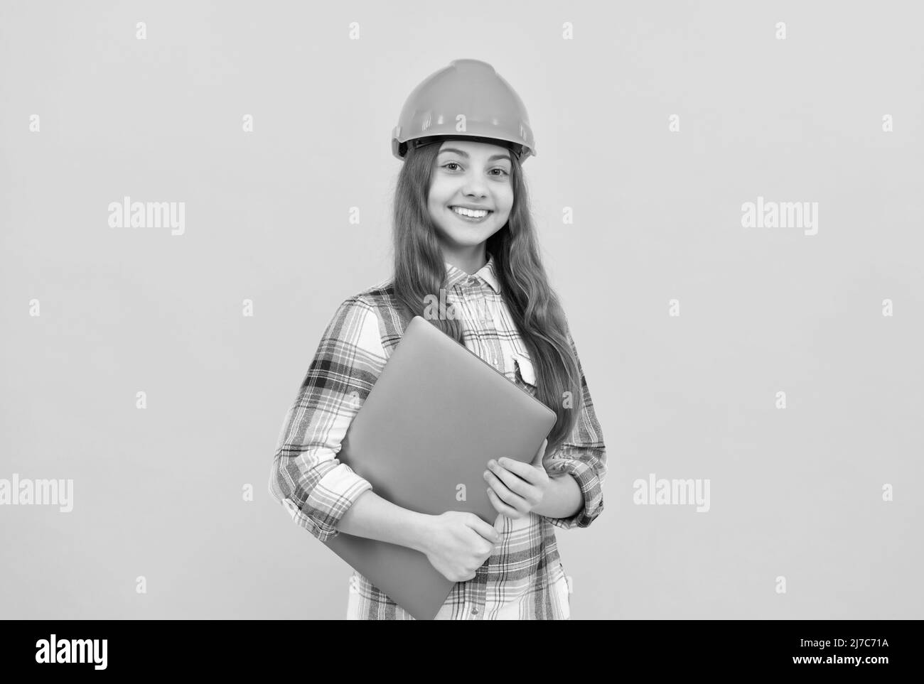 Happy teen Mädchen in Helm und karierte Hemd halten Computer, modernes Leben Stockfoto