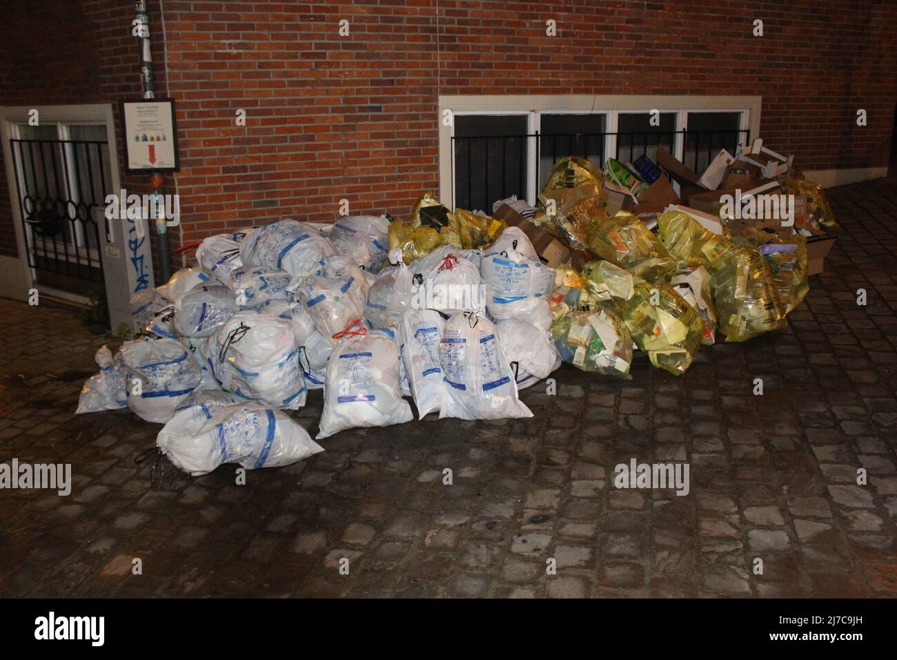 Abfall- und Recycling-Säcke in einem Stapel, der auf die Abholung wartet. Überfließende Abfälle am Tag der Müllabfuhr (Ixelles, Belgien) Stockfoto