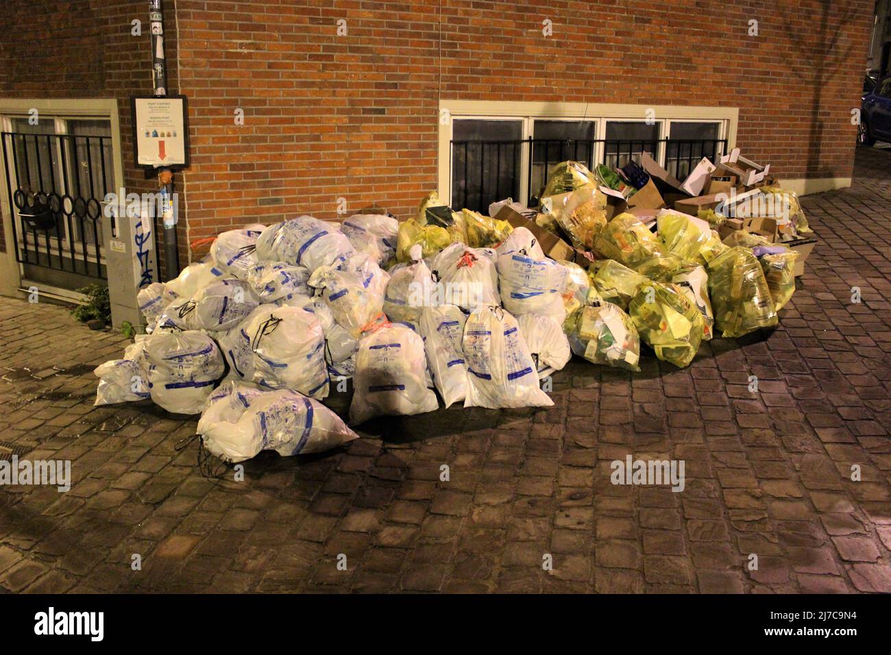 Abfälle und Recycling-Säcke in einem Stapel warten auf die Abholung. Überfließende Abfälle am Tag der Müllabfuhr (Ixelles, Belgien) Stockfoto