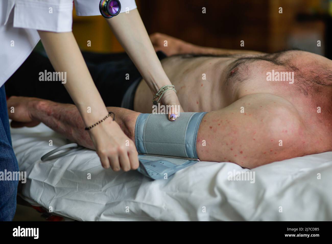 Die junge medizinische Frau legt einen Blutdruck-Monitor oder ein Blutdruckmessgerät auf den Arm eines männlichen Patienten. Stockfoto