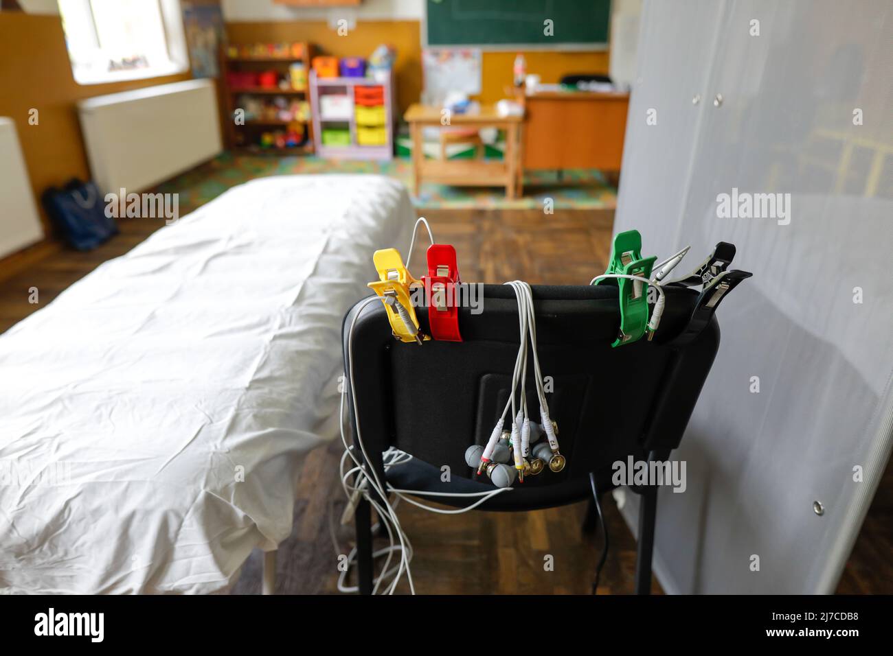 Details zur Schärfentiefe (selektiver Fokus) mit Elektroden eines Elektrokardiographie-Geräts auf dem Stuhl eines medizinischen Schranks im Stockfoto