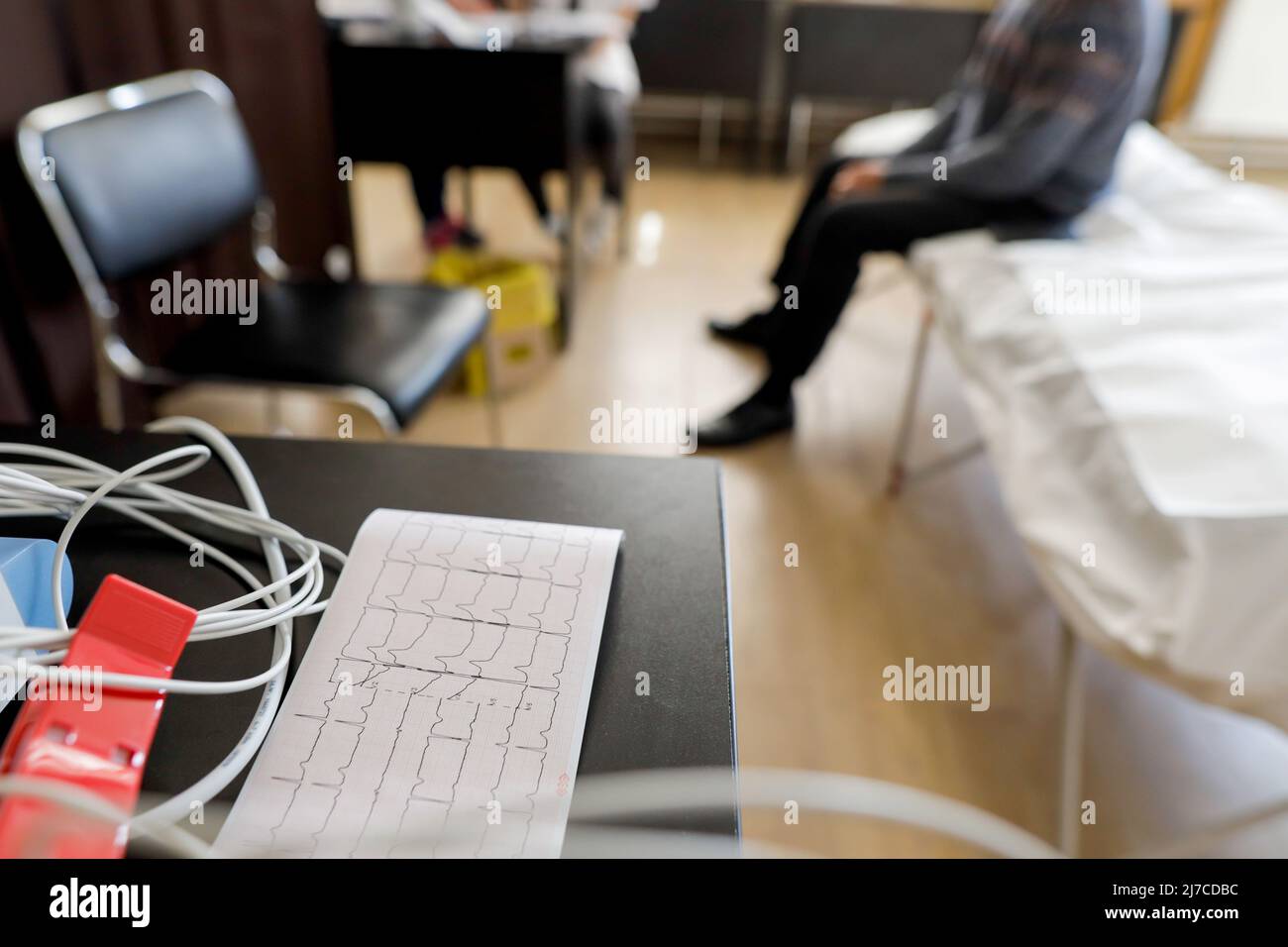 Details zur Schärfentiefe (selektiver Fokus) mit Elektroden aus einem Elektrokardiographie-Gerät und einem Elektrokardiogramm. Stockfoto