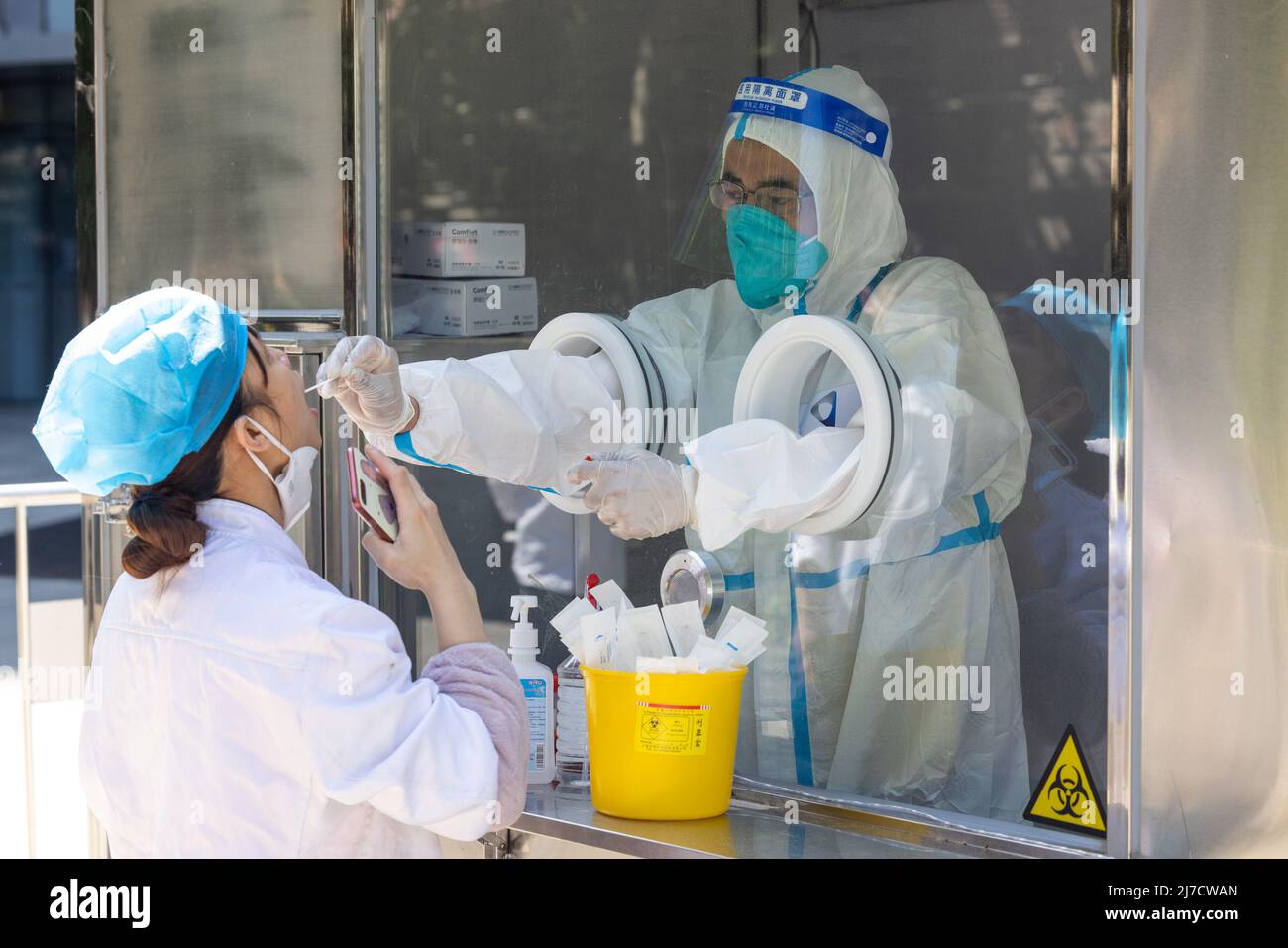 (220508) -- SHANGHAI, 8. Mai 2022 (Xinhua) -- Ein Mitarbeiter nimmt eine Abstrichprobe einer Frau zum Nukleinsäuretest im Bezirk Huangpu, Shanghai im Osten Chinas, 8. Mai 2022. Shanghai hat in Übereinstimmung mit der epidemischen Situation stationäre und mobile Säureprüfstände in Wohngebieten, Büroräumen, Gewerbegebieten und in der Nähe von U-Bahn- und anderen öffentlichen Verkehrsstationen eingerichtet. (Xinhua/Jin Liwang) Stockfoto