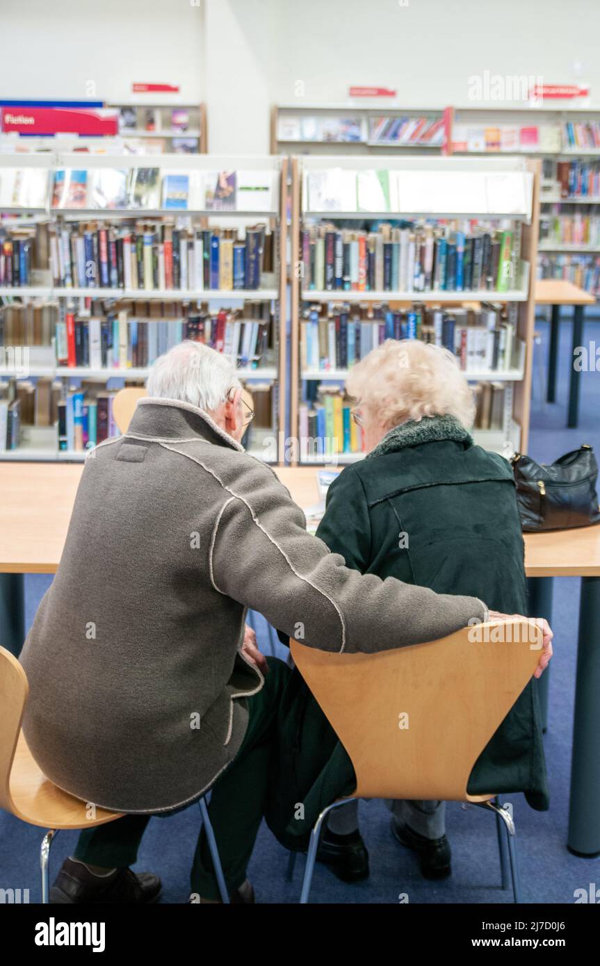 Elderley Paar liest zusammen in einer lokalen Bibliothek Stockfoto