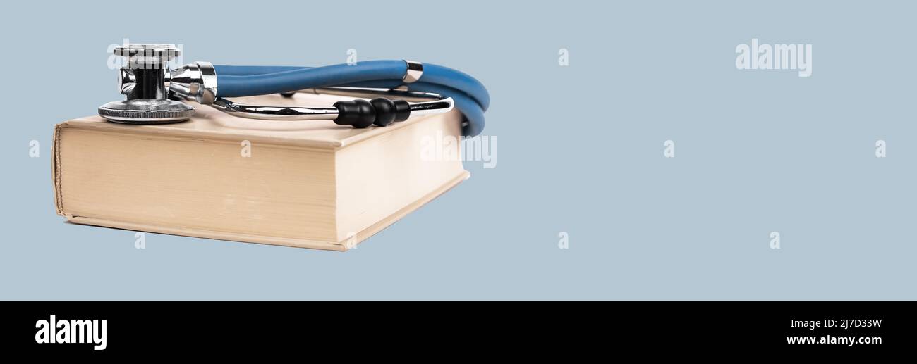 Banner mit medizinischem Bildungskonzept. Buch mit Stethoskop auf blauem Hintergrund. Lernen von Informationen über Medizin, Gesundheitsversorgung, Behandlung. Speicherplatz kopieren. Hochwertige Fotos Stockfoto