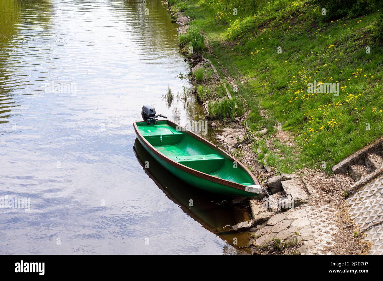 Angler Boot an einem sonnigen Tag auf einem grasbewachsenen Ufer vertäut. Stockfoto
