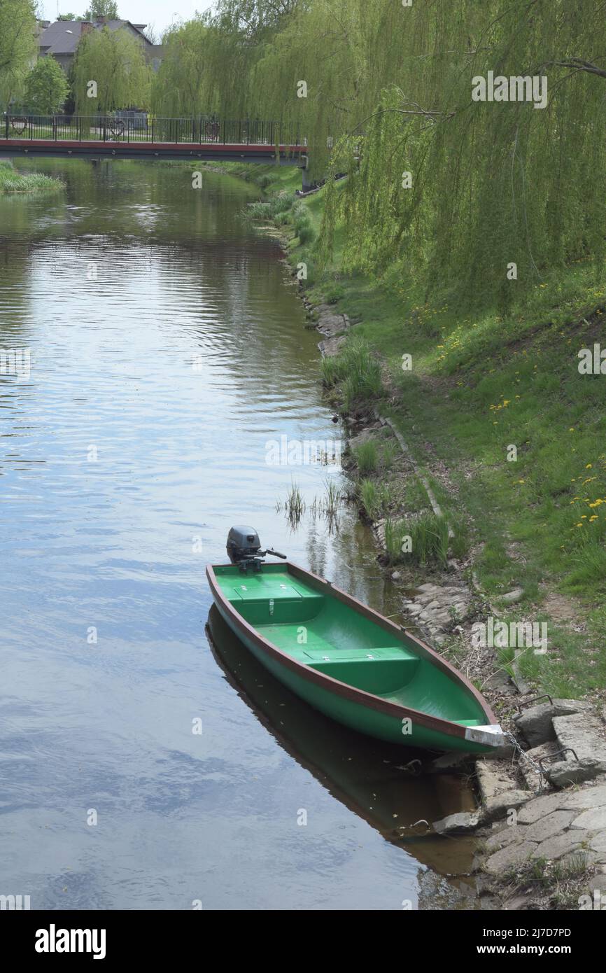 Angler Boot an einem sonnigen Tag auf einem grasbewachsenen Ufer vertäut. Stockfoto