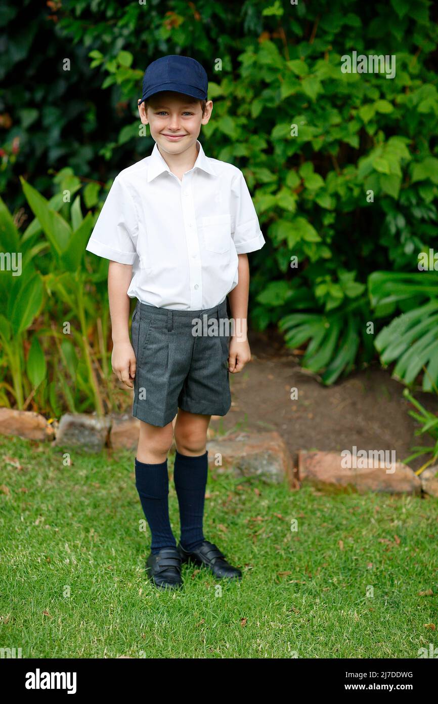 Stolzer junger Schuljunge, der am ersten Schultag in seiner Uniform lächelt Stockfoto