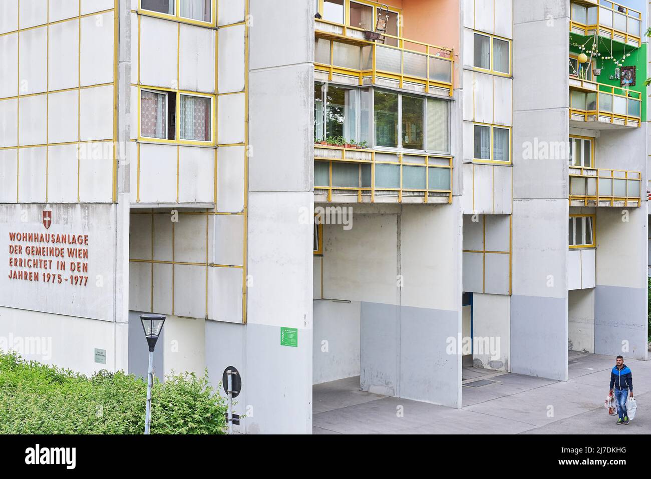 Ein einsamer Mann trägt Shopping zwischen den Blöcken einer Wohnsiedlung Stockfoto