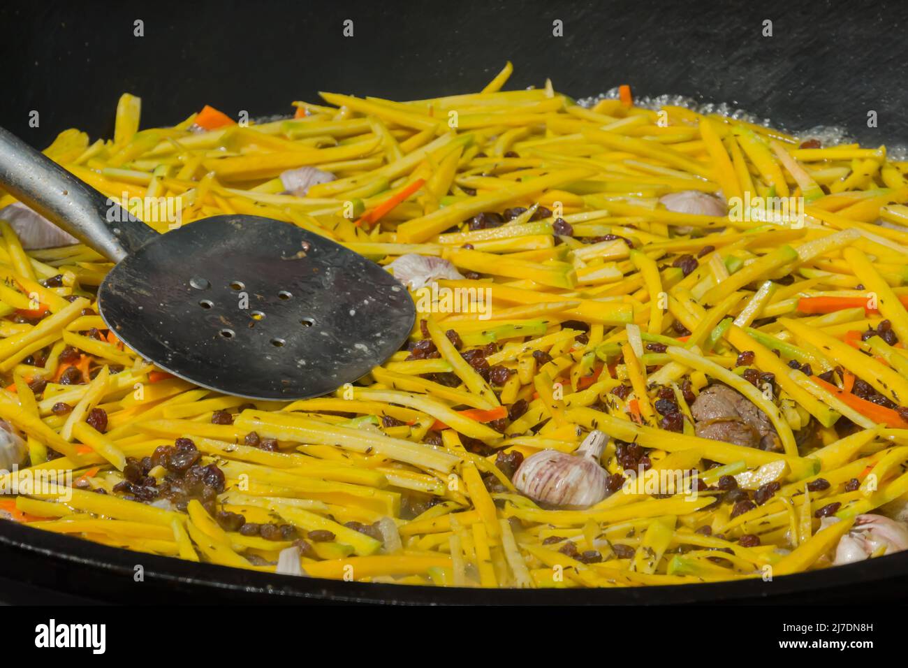 Kochen von Kartoffeln, Karotten-Scheiben, Knoblauch für usbekische Pilaf in einem riesigen Kessel Stockfoto