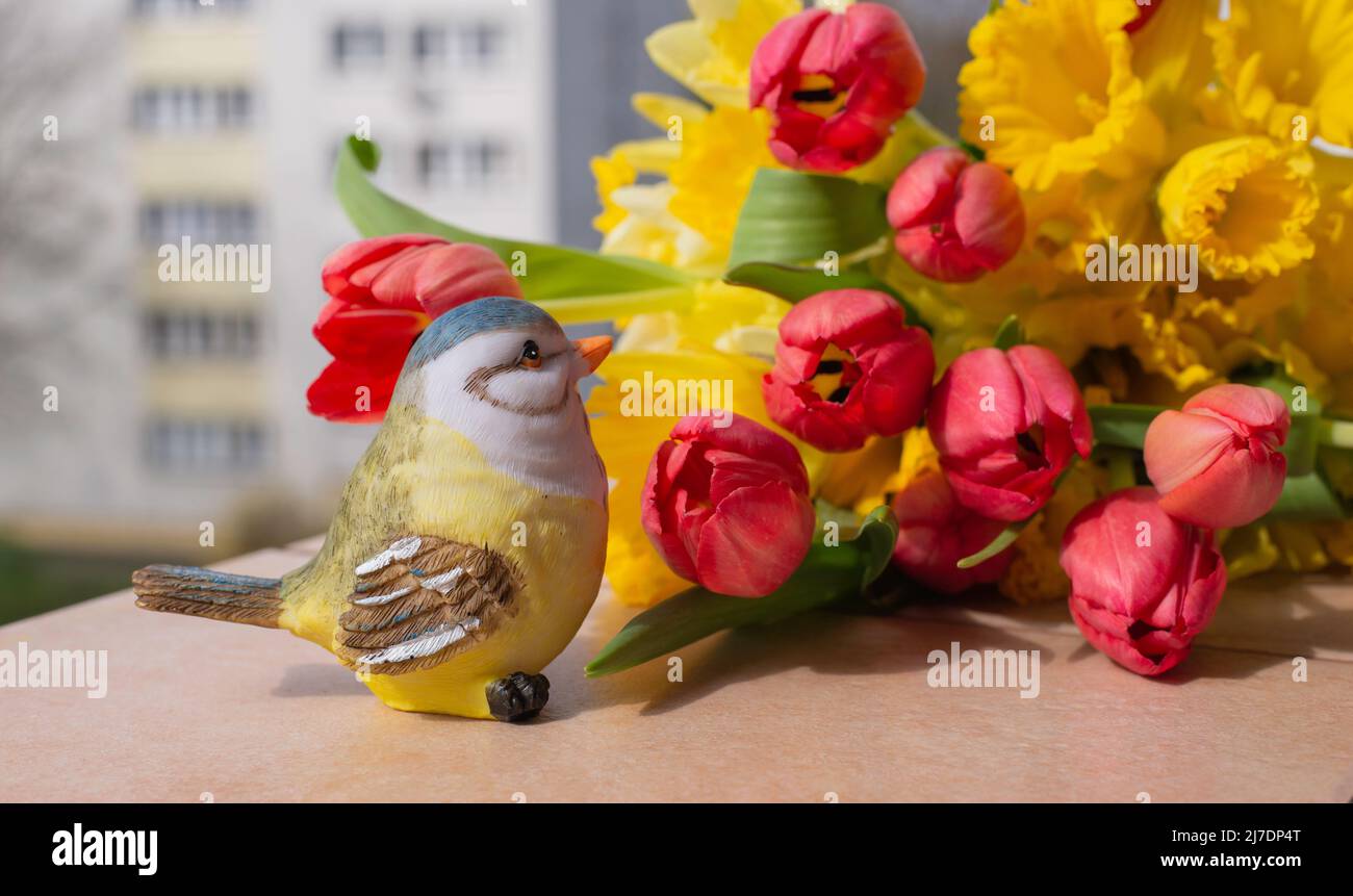 Rote Tulpen und gelbe Narzisse in einem wunderschönen Frühlingsstrauß. Blumenstrauß im Frühling auf einem Fenster mit Blick auf die Stadt Stockfoto