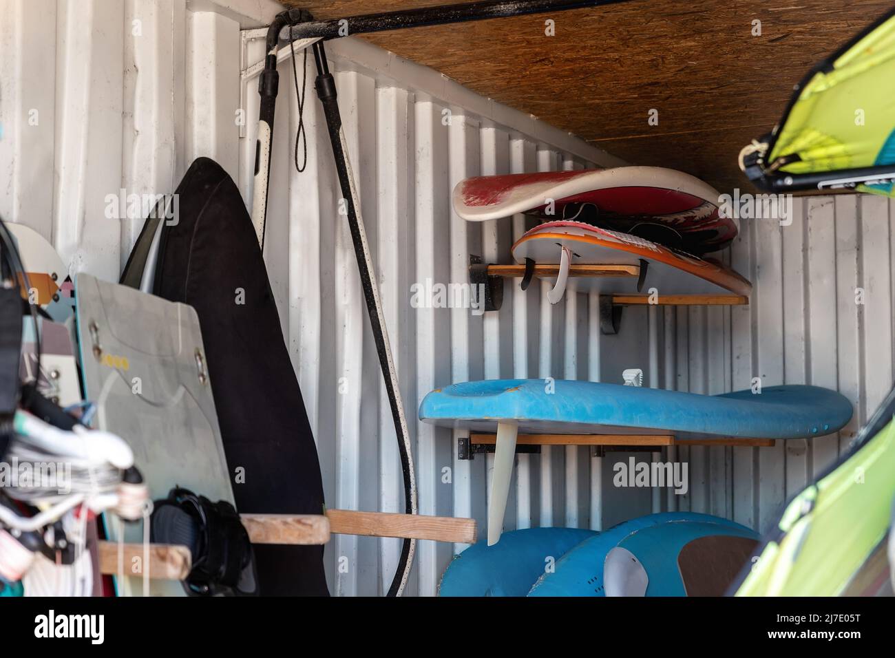 Innenraum der Windsurfbretter Lagerraum in alten rostigen Metall-Versandbehälter-Box mit Regalen an der Wand. Gebrauchte schäbige Surfbretter, Verleih und Lager Stockfoto