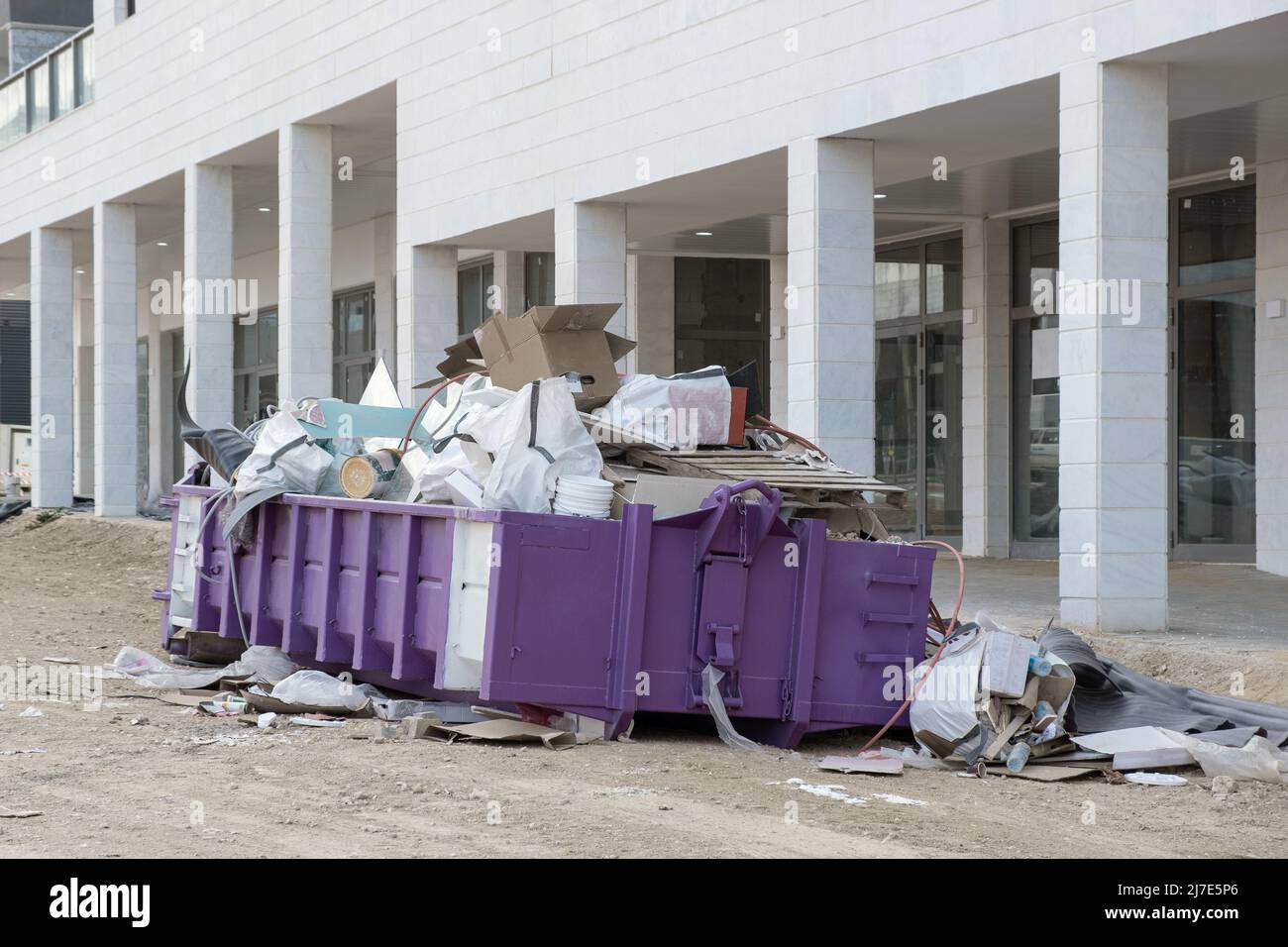 Bauabfälle in einem riesigen überlasteten Müllcontainer. Behälter aus Metall, gefüllt mit Bauabfällen, Schutt in der Nähe einer Baustelle. Stockfoto