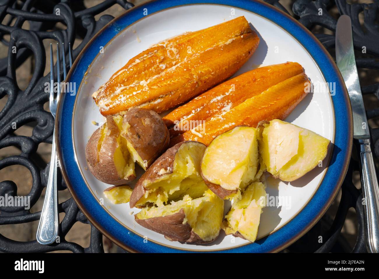 Mittags zwei saftige Kipper mit gebackenen Kartoffeln auf einem Tisch im Freien Stockfoto