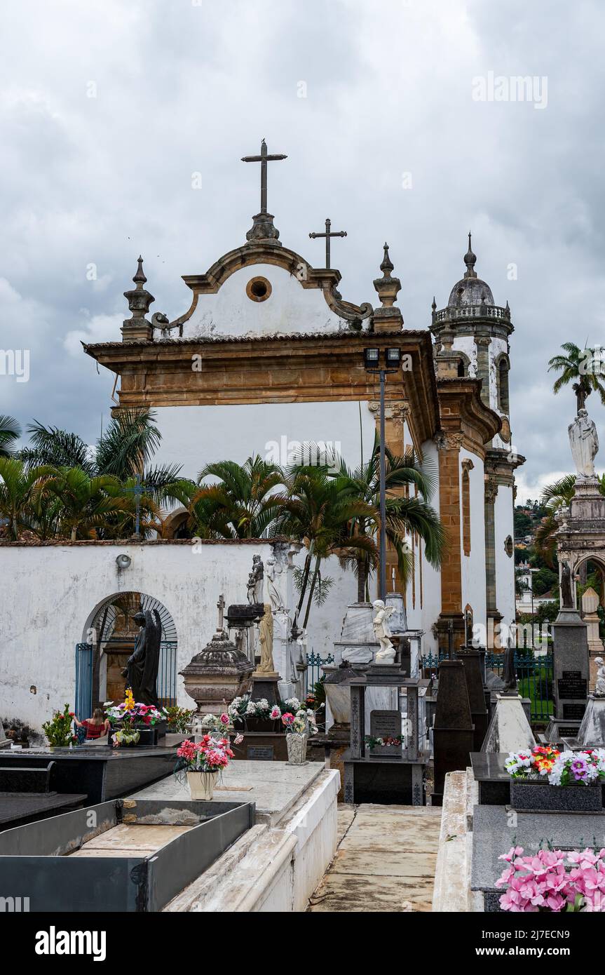 Teilansicht der Rückseite der Kirche Sao Francisco de Assis und des Friedhofs unter stark bewölktem Himmel. Stockfoto