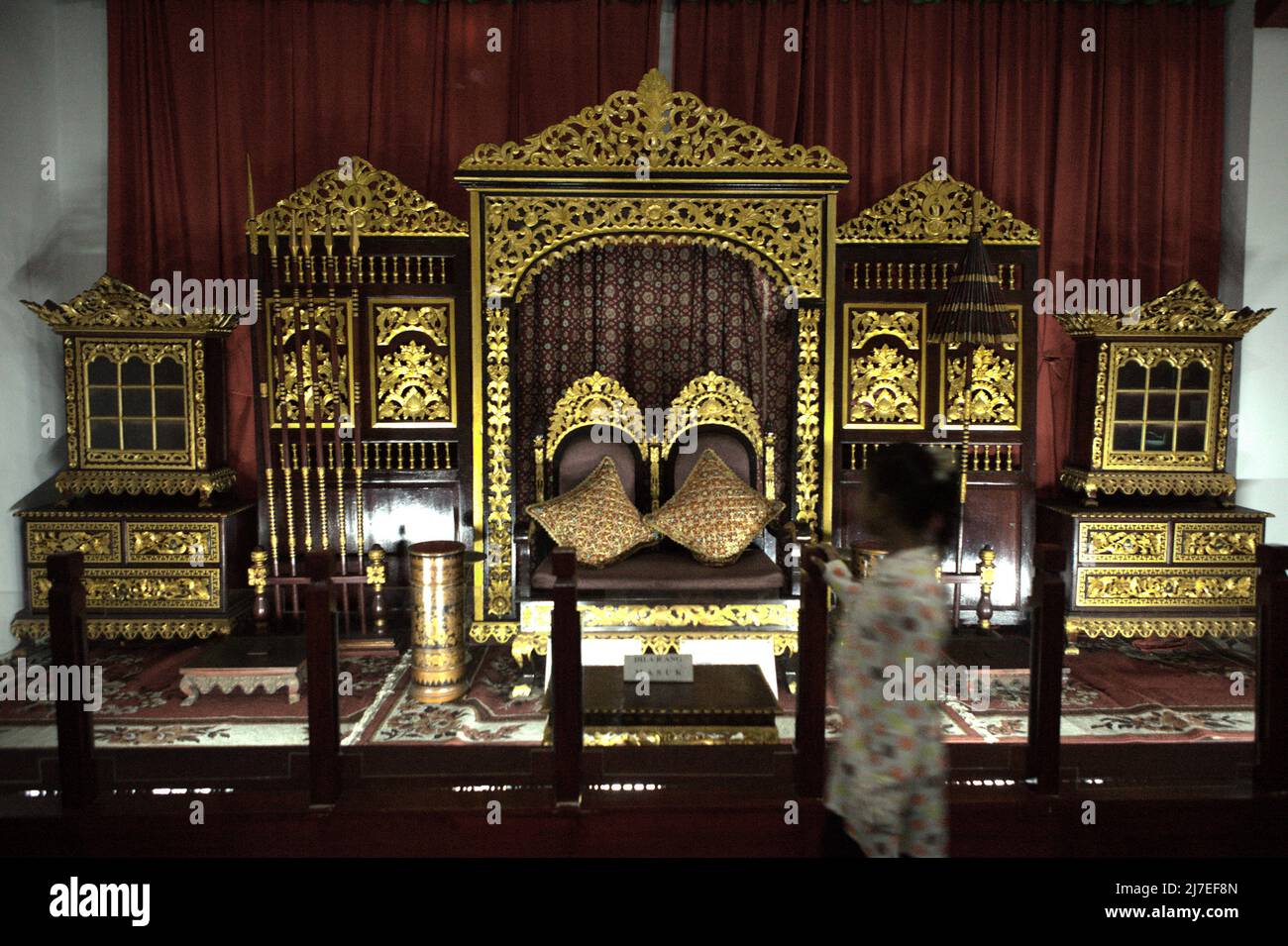 Ein Kind, das vor dem Thron des Sultanats von Palembang steht, fotografiert im Sultan Mahmud Badaruddin II Museum in Palembang, Süd-Sumatra, Indonesien. Stockfoto