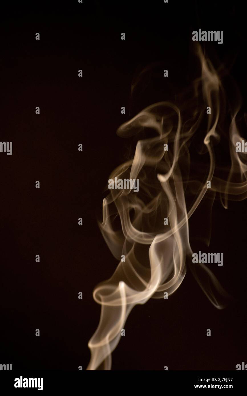 Goldgelb wirbelndes, aufsteigendes Rauchmuster auf schwarzem Hintergrund, Foto könnte als Hintergrund, Rauchstruktur, abstrakt oder allgemeiner Bestand verwendet werden Stockfoto