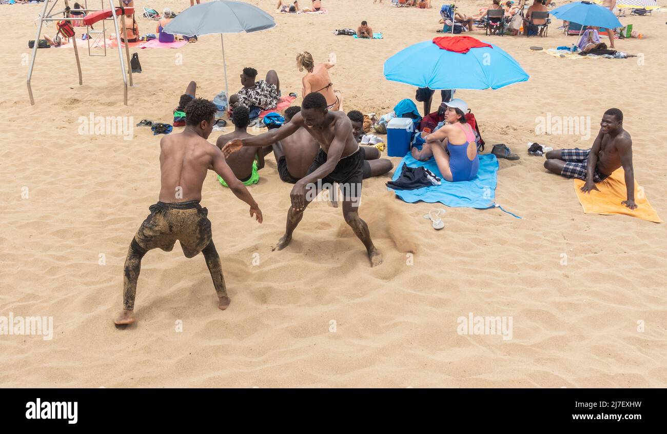 Las Palmas, Gran Canaria, Kanarische Inseln, Spanien. 8.. Mai 2022. Junge Männer südlich der Sahara, die in einem Bergdorf untergebracht sind, ringen den Tag am Stadtstrand von Las Palmas auf Gran Canaria mit Spaß. Dies sind einige der Glücklichen, die die gefährliche Überfahrt von Afrika in kleinen Booten gemacht haben. Am Sonntag starben mindestens 44 Migranten bei dem Versuch, von Afrika auf die Kanarischen Inseln (Europa) zu reisen. Im Jahr 2021 4.016 starben Menschen beim Versuch, dieselbe Überfahrt zu machen. Kredit: Alan Dawson/ Alamy Live Nachrichten. Stockfoto