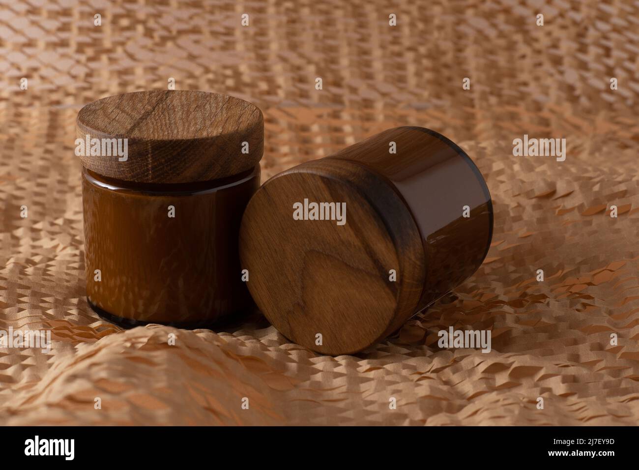 Behälter für Kosmetik und Cremes. Glas braun mit Holzdeckel. Beigefarbener Hintergrund. Monochromes Konzept. Für ein Etikett platzieren. Cremegläser. Schönheit und Pflege. Minimalismus Stockfoto