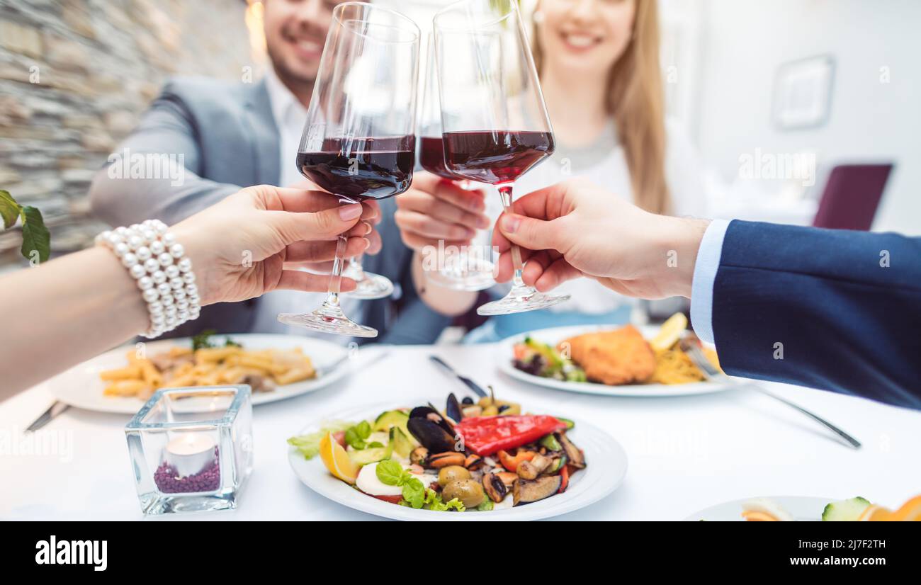 Nahaufnahme der Hände von Gästen im Restaurant mit Gläsern Rotwein Stockfoto