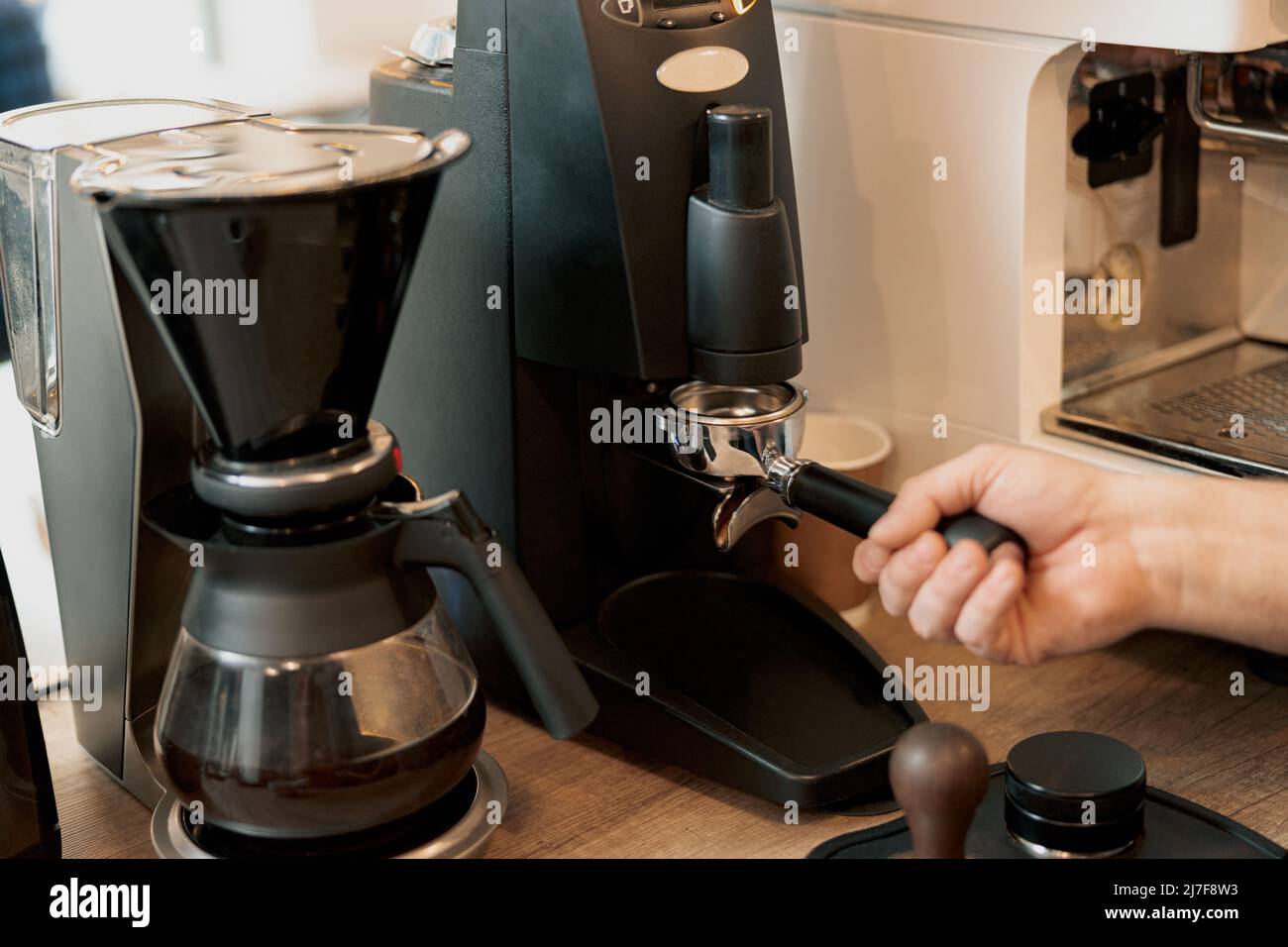 Nahaufnahme des Barista beim Kaffeemahlen, Zubereitung des Espresso Shot Stockfoto