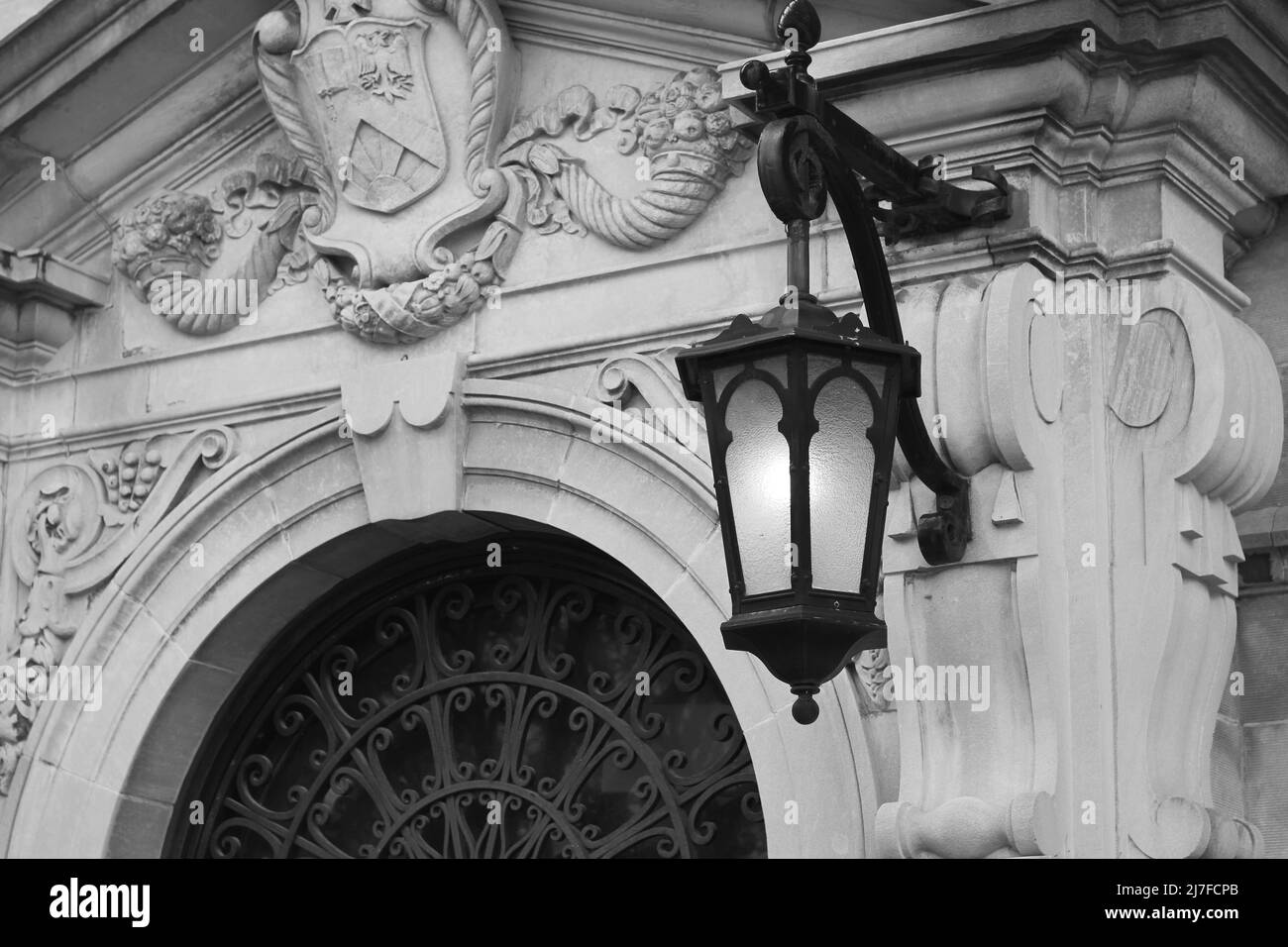 Historische gusseiserne dekorative Straßenlampe, die in Schwarz und Weiß an der Wand des Steingebäudes hängt. Stockfoto