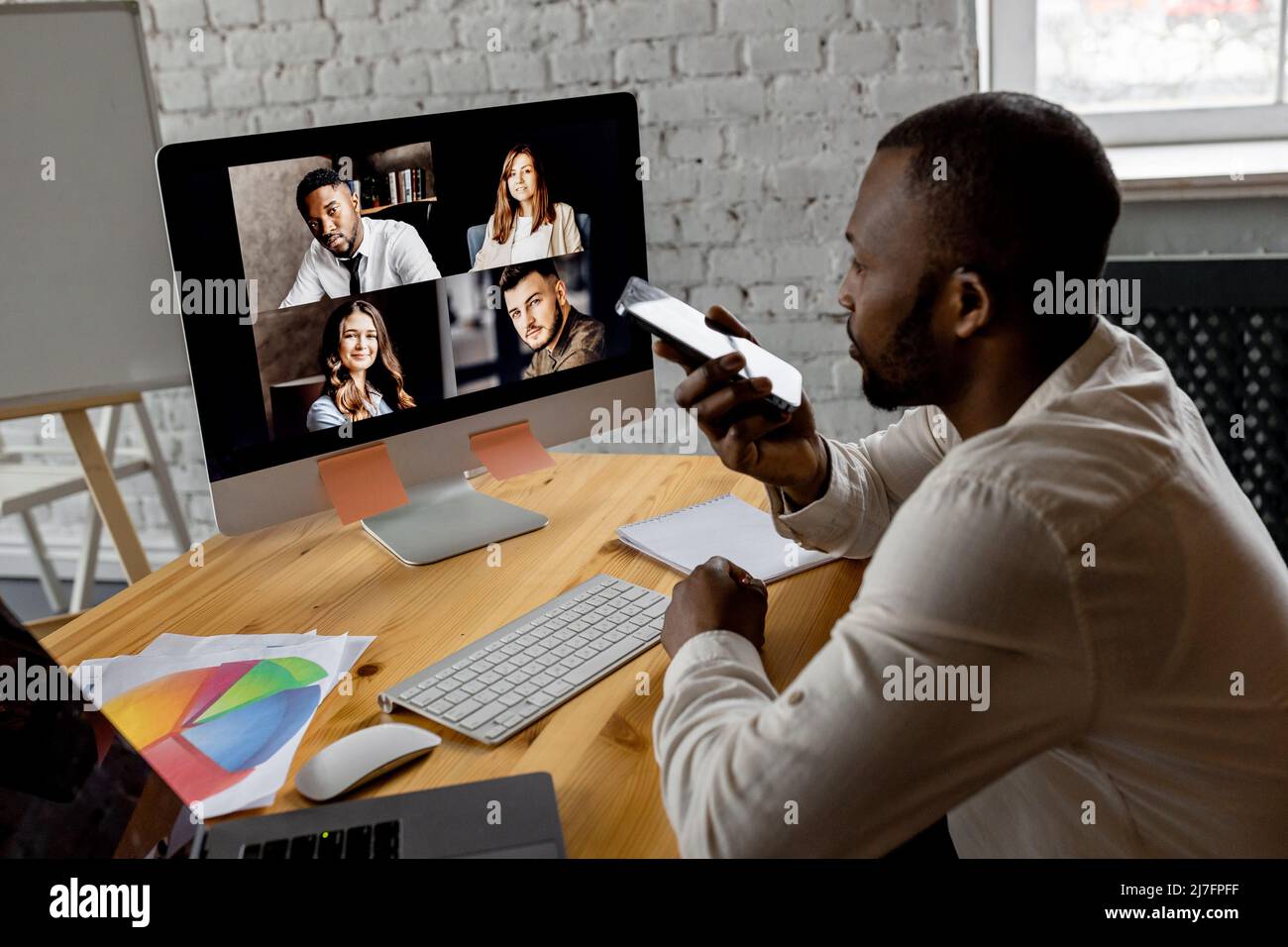 afroamerikanischer freiberuflicher Mitarbeiter winkt Kollegen bei einem Videotreffen mit einem Laptop willkommen. Stilvoller, freundlicher Geschäftsmann, der ein Videomeeting hat Stockfoto