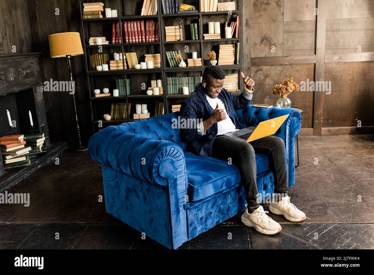 Lächelnd junger afroamerikanischer Student oder Geschäftsmann professionell machen Geschäftsanruf auf dem gelben Laptop zu Hause und genießen die Geschäftsabläufe Gespräch Stockfoto