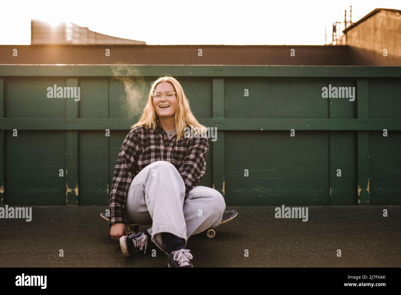 Porträt von lächelnden Teenager-Mädchen auf Skateboard sitzen Stockfoto