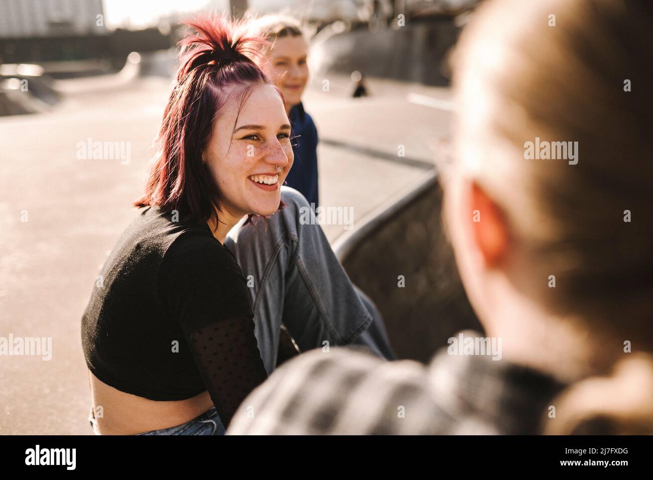 Lächelnde Mädchen im Teenageralter sitzen im Skatepark Stockfoto
