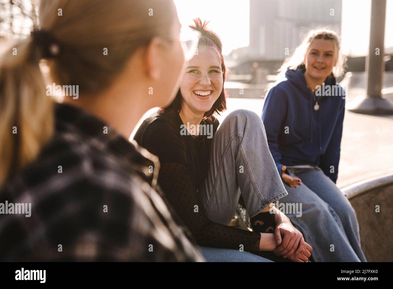 Lächelnde Mädchen im Teenageralter sitzen im Skatepark Stockfoto