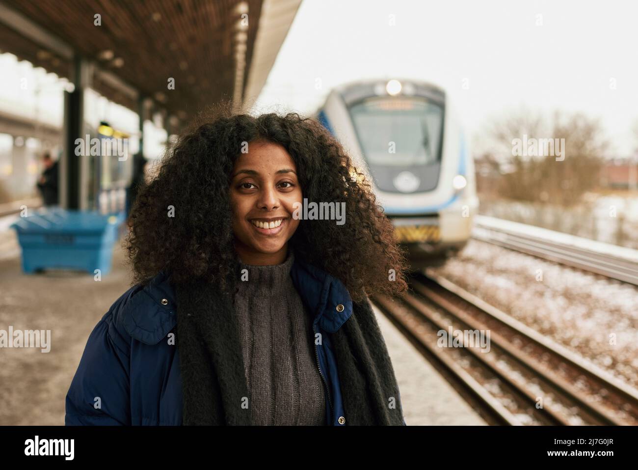 Lächelnde Frau, die am Bahnhof steht Stockfoto