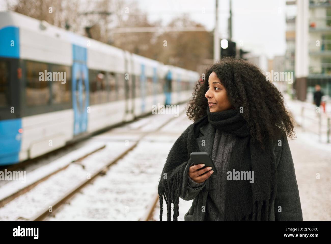 Frau am Bahnhofssteig mit Mobiltelefon Stockfoto