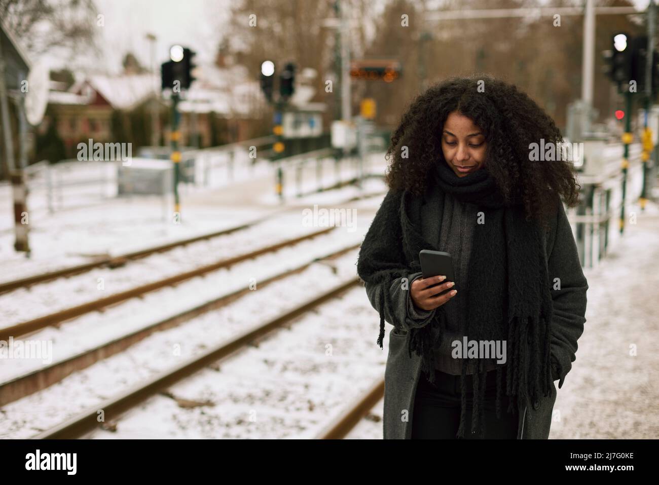 Frau am Bahnhofssteig mit Handy Stockfoto