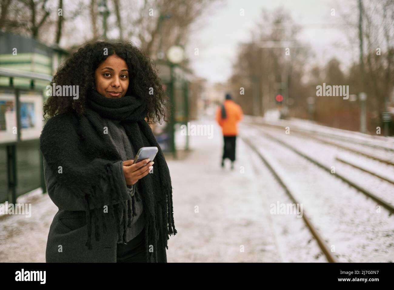 Frau am Bahnhofssteig mit Handy Stockfoto