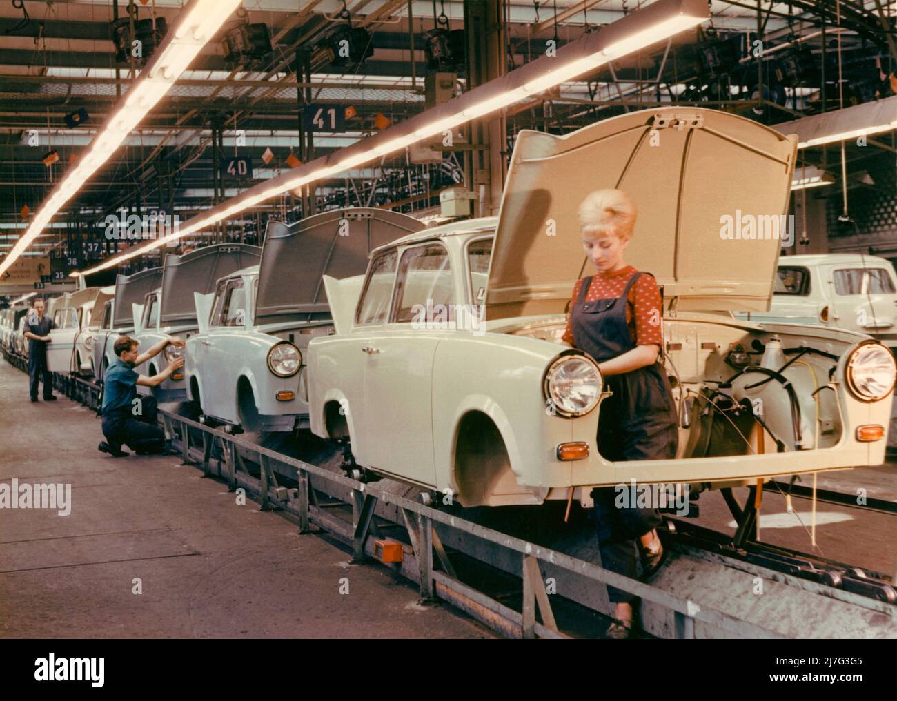 Der Trabant. VEB Sachsenring Automobilwerk. Trabant begann 1957 mit der Herstellung und die Produktion dauerte bis 1991. Insgesamt wurden 3 051385 Trabant hergestellt. Trabant wurde als Antwort von Ostdeutschland auf Volkswagen und die Vision eines Autos für die Menschen entwickelt. Es hieß Trabbi oder Trabi und wurde das häufigste Auto in Ostdeutschland. Trabant wurde während des Sturzes der Berliner Mauer zu einem Symbol für Ostdeutschland. Aufgenommen in der Trabant Autofabrik in Sachsen im Jahr 1960s. Die junge Frau, die an der Montagelinie steht, hat die typische Frisur der 1960s, die Be Stockfoto
